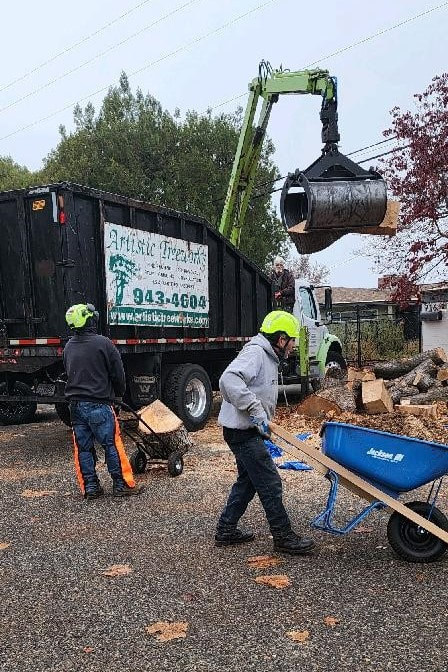 Wood products being removed from jobsite, using grapple truck, hand truck, and wheelbarrow.