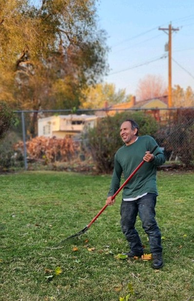 Man using a rake to remove debris from a yard.